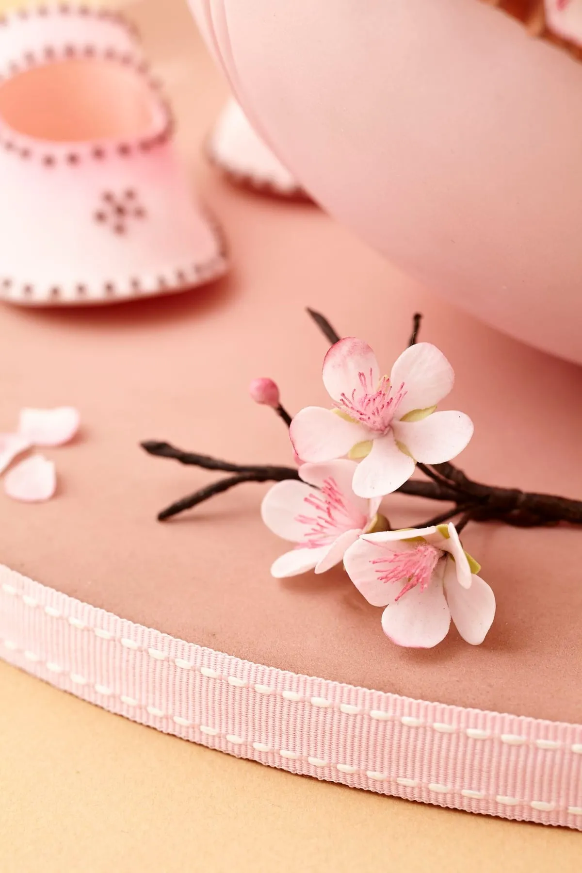 Pink sugar blossoms next to fondant baby shoes
