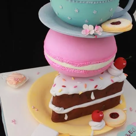 A stacked cake: a teacup, a pink macaron and a slice of cake